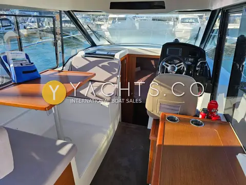 Jeanneau Merry Fisher 895: wheelhouse with wooden dinette table to port and helm seat to starboard