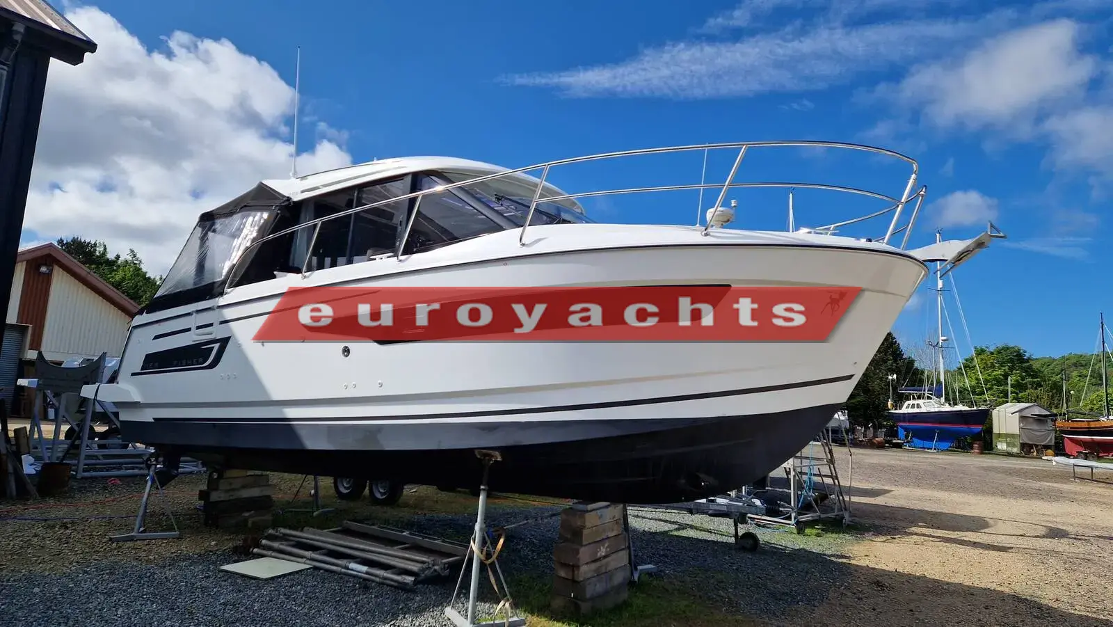 Jeanneau Merry Fisher 895 Offshore: white hull with dark window band ashore on stands in a boatyard