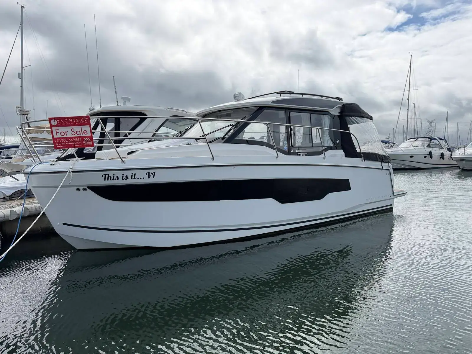 Jeanneau Merry Fisher 895 S2: starboard bow view of the white hull with dark window band, moored in a marina