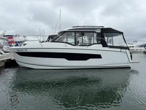 Jeanneau Merry Fisher 895 S2: starboard side profile showing wheelhouse, hull windows and canvas aft enclosure in the marina