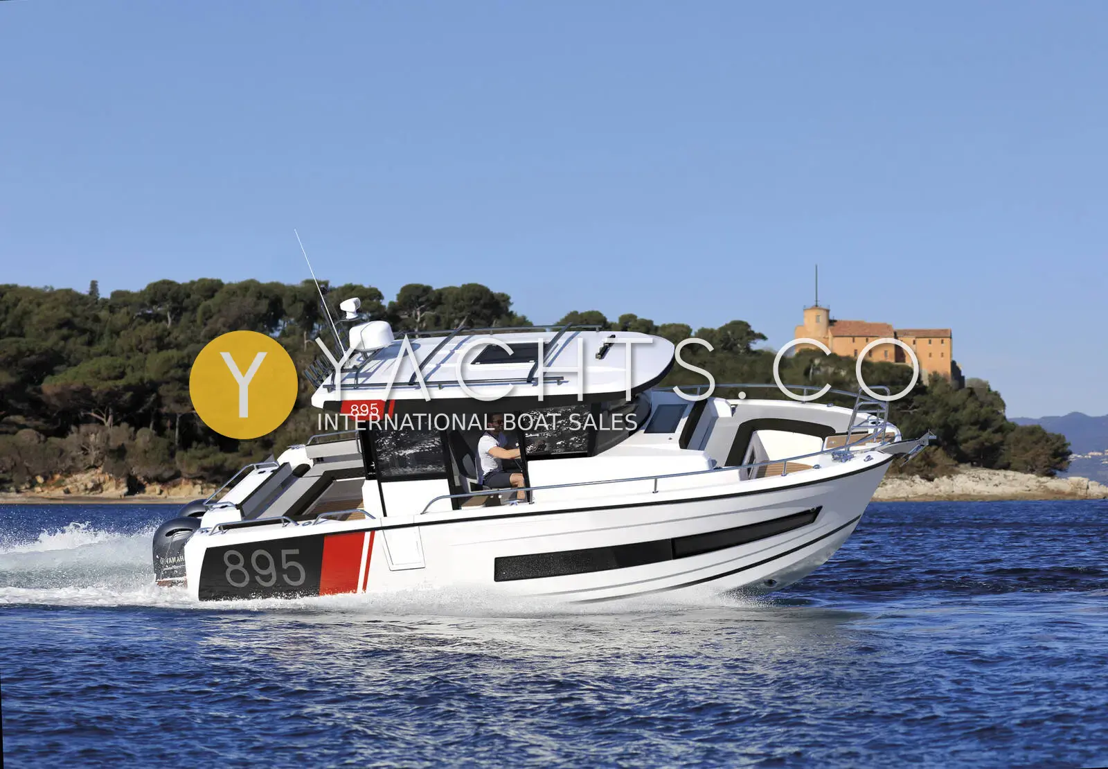 Jeanneau Merry Fisher 895 Sport Offshore: white hull with red 895 graphics under way at speed, wooded coastline and fort behind