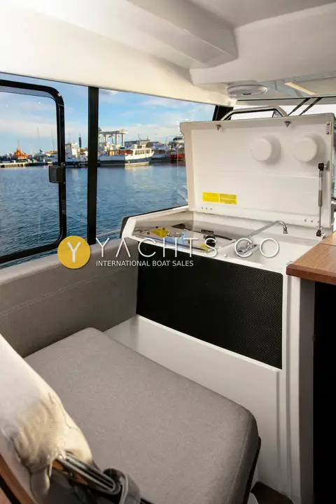 Jeanneau Merry Fisher 895 Sport Offshore: wheelhouse seat beside an open galley unit with hob, overlooking a harbour