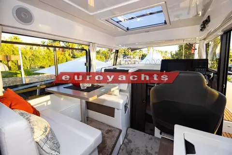 Jeanneau Merry Fisher 895 Sport S2: wheelhouse saloon with orange cushions, opening roof hatch and helm seat beyond