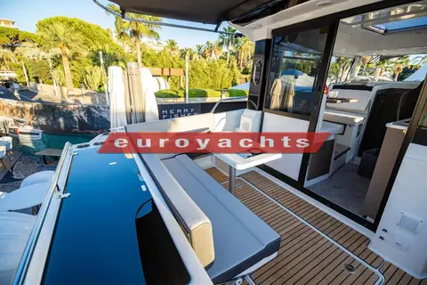 Jeanneau Merry Fisher 895 Sport S2: aft cockpit with L-shaped bench, table, teak-effect floor and open wheelhouse door