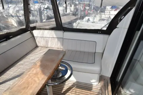 Jeanneau NC 33: cockpit settee with light grey cushions, teak table and teak-laid sole