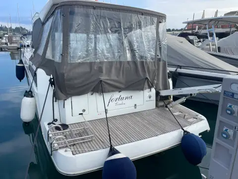 Jeanneau NC 33: stern view showing teak swim platform, boarding ladder and full cockpit canvas enclosure