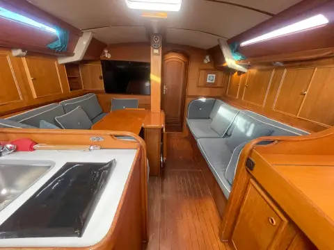 Jeanneau Olympic Sea 42 Sun Legend Hull: saloon from the galley, with blue upholstered seating, wood joinery and wall-mounted TV