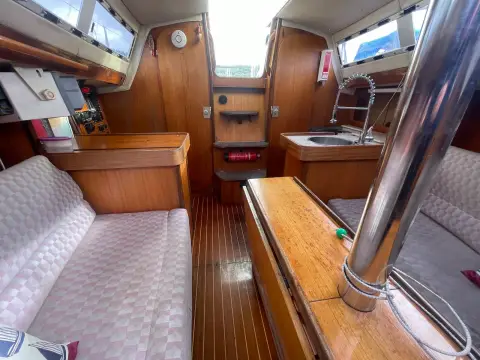 Jeanneau Sun Dream 28: saloon looking aft towards companionway, galley sink and navigation area with teak sole