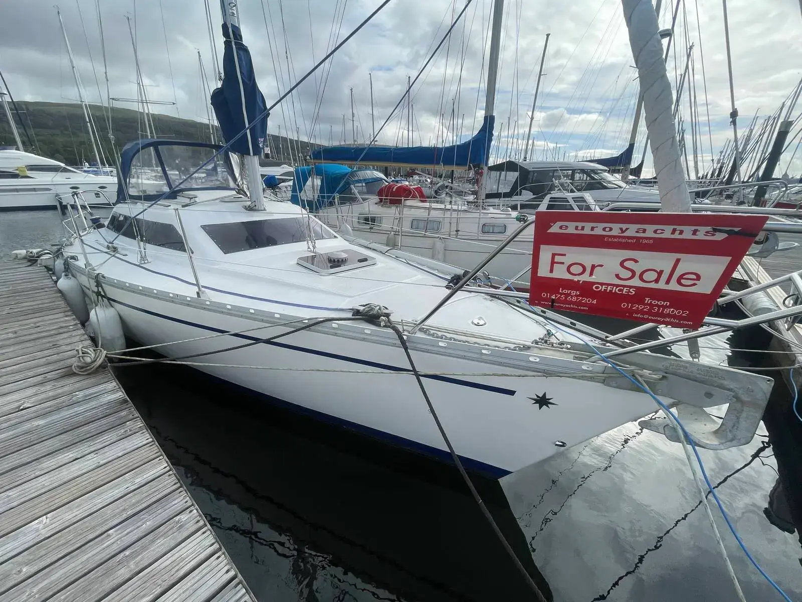 Jeanneau Sun Dream 28: white sloop moored stern-on at a pontoon with a For Sale sign on the guardrail