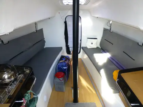 Jeanneau Sun Fast 3300: saloon looking forward with grey settees, gas hob to port and mast post