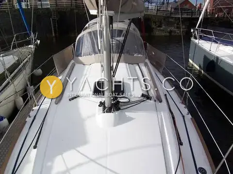 Jeanneau Sun Odyssey 30I: foredeck looking aft to mast, deck hatch and sprayhood in a stone-walled dock