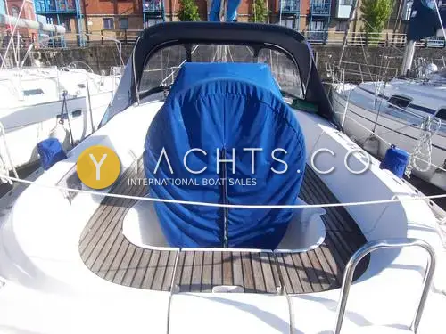 Jeanneau Sun Odyssey 32.2: cockpit with teak seats, blue wheel cover and dark sprayhood, seen from the stern