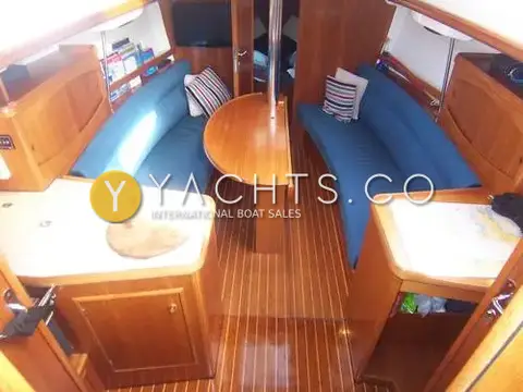 Jeanneau Sun Odyssey 32.2: saloon with blue upholstered settees, folding wooden table and varnished wood flooring