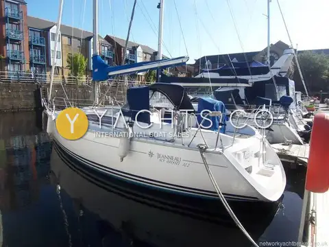 Jeanneau Sun Odyssey 32.2: port side view of the white hull moored in a marina beside brick apartments