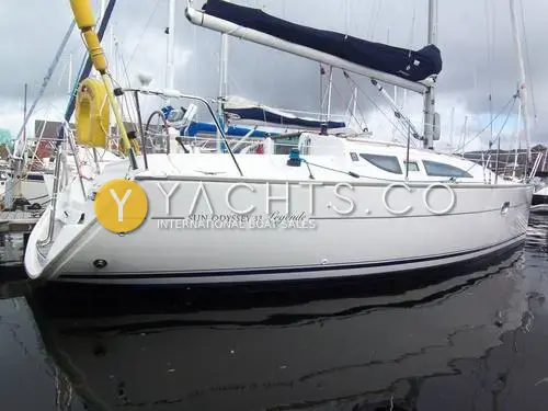 Jeanneau Sun Odyssey 32 Legend: white hull in profile at a marina berth, Sun Odyssey 32 Legende lettering, mainsail under navy cover