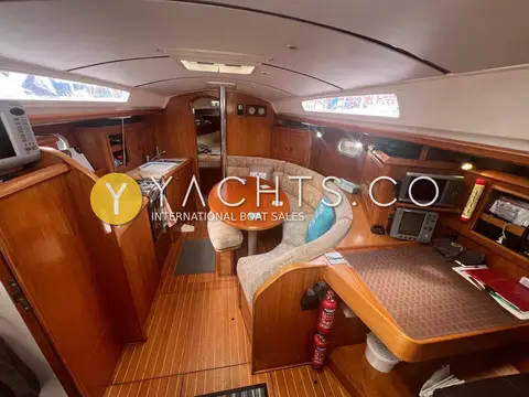 Jeanneau Sun Odyssey 34.2: saloon with curved seating, round table, galley to port and chart table to starboard