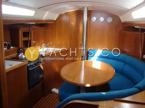 Jeanneau Sun Odyssey 34.2: saloon with blue curved settee, round wooden table, galley with two-burner hob and sink