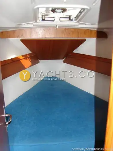 Jeanneau Sun Odyssey 34.2: forward cabin V-berth with blue upholstery, wooden shelves and overhead deck hatch