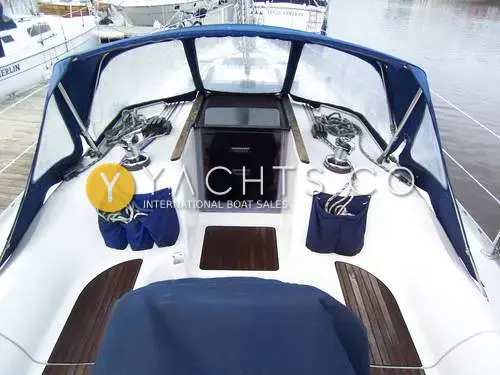 Jeanneau Sun Odyssey 34.2: cockpit looking forward under blue sprayhood, with winches, rope bags and teak seat panels