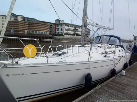 Jeanneau Sun Odyssey 34.2: white hull alongside a pontoon in a harbour, with blue sprayhood and fenders out