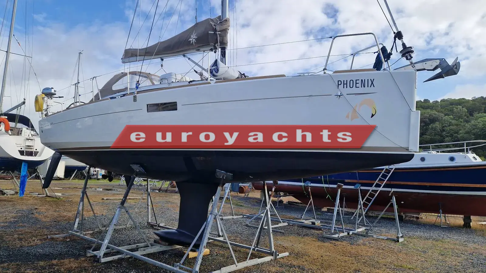 Jeanneau Sun Odyssey 349: white hull ashore on stands in a boatyard, viewed from the port bow