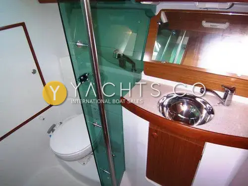 Jeanneau Sun Odyssey 35: heads compartment with green glass shower screen, stainless steel basin and wood-trimmed mirror
