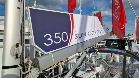 Jeanneau Sun Odyssey 350: boom with branded 350 sail cover, flags flying at a boat show