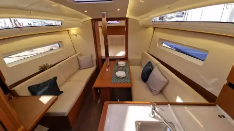 Jeanneau Sun Odyssey 350: saloon with light upholstery, hull windows, central table and wood joinery