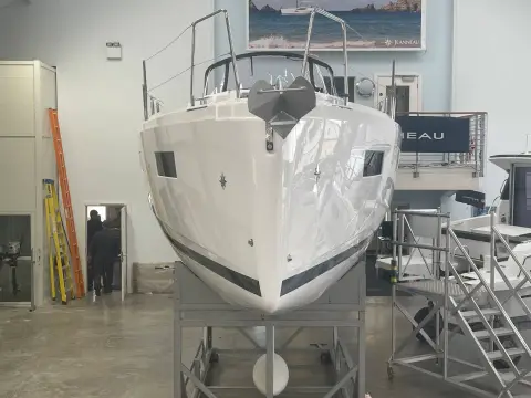 Jeanneau Sun Odyssey 350: bow view of the white hull with dark sheer stripe, on a showroom cradle