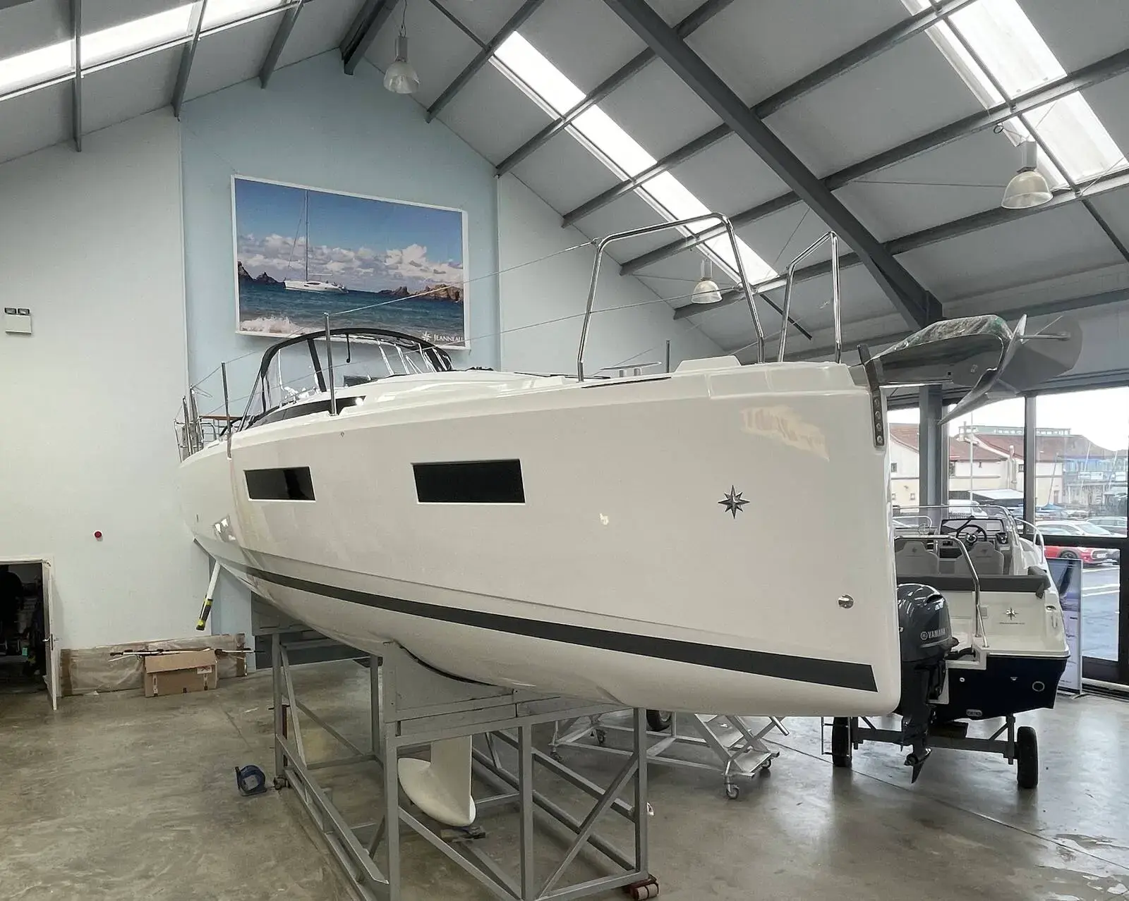 Jeanneau Sun Odyssey 350: white hull on a cradle inside the Largs showroom, viewed from the port side