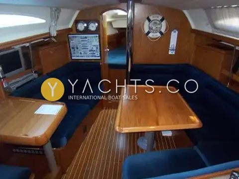 Jeanneau Sun Odyssey 37: saloon with blue upholstery, teak table on U-shaped seating and navigation area to port