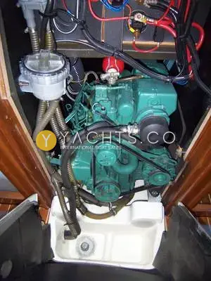 Jeanneau Sun Odyssey 37: engine bay beneath the companionway steps showing the green diesel engine and raw water filter