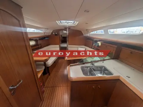 Jeanneau Sun Odyssey 37 Legende: saloon looking forward, cream seating, wooden tables and galley sink in foreground