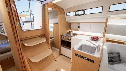 Jeanneau Sun Odyssey 385: companionway steps beside galley with stove, sink and white worktop, manufacturer render
