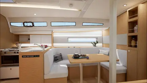 Jeanneau Sun Odyssey 385: saloon dining area with U-shaped seating, wooden table and galley with oven to the left