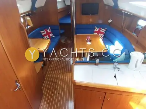 Jeanneau Sun Odyssey 40: saloon with blue upholstery, wooden table, flat-screen TV and galley worktop in foreground