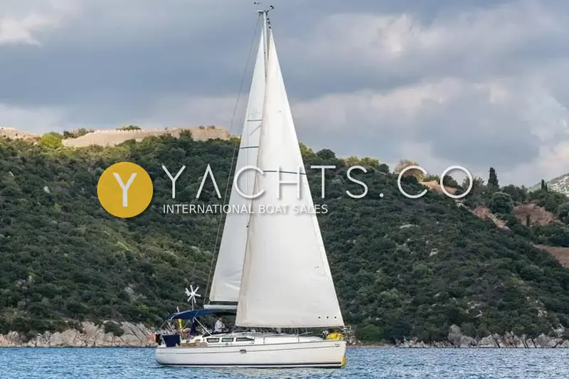 Jeanneau Sun Odyssey 40.3: sailing under full main and genoa past a wooded hillside with a fortress wall above