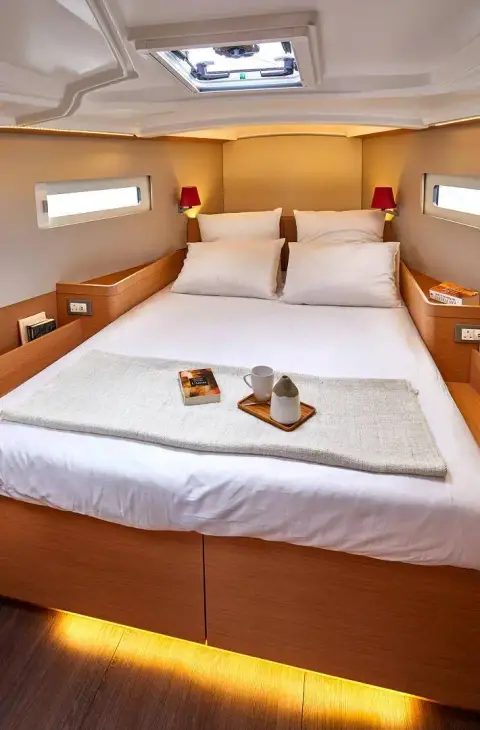 Jeanneau Sun Odyssey 410: double berth with white bedding, red reading lamps, overhead hatch and under-berth lighting
