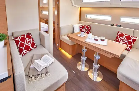 Jeanneau Sun Odyssey 410: saloon seating with table on twin chrome legs, red patterned cushions and hull windows