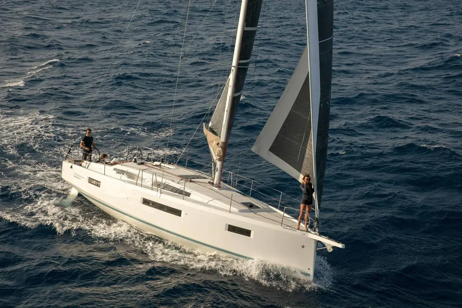 Jeanneau Sun Odyssey 410: white hull sailing at speed under main and genoa with crew on deck and at the bow