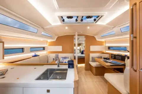 Jeanneau Sun Odyssey 415: bright saloon with hull windows, L-shaped galley with sink, and forward-facing chart table
