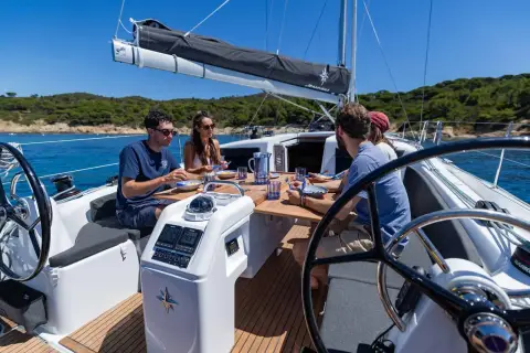 Jeanneau Sun Odyssey 415: cockpit under sail with teak floor, twin wheels and crew seated at the table
