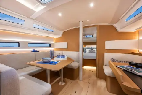 Jeanneau Sun Odyssey 415: saloon with hull windows, L-shaped seating, table and view forward to the cabin
