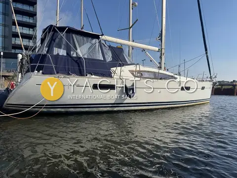 Jeanneau Sun Odyssey 42 DS: bow and starboard side with navy sprayhood and bimini, alongside a pontoon