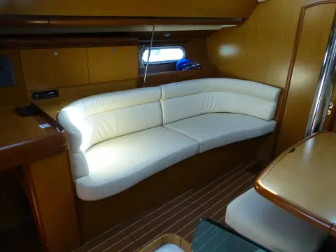 Jeanneau Sun Odyssey 42DS: saloon bench settee to port in cream leather beneath a hull portlight