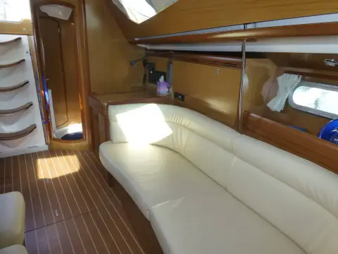 Jeanneau Sun Odyssey 42DS: port settee with companionway steps and wood panelling in sunlight