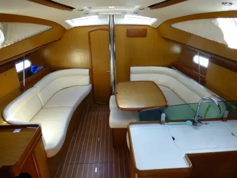 Jeanneau Sun Odyssey 42DS: deck saloon looking forward with cream upholstery, dining table and galley counter