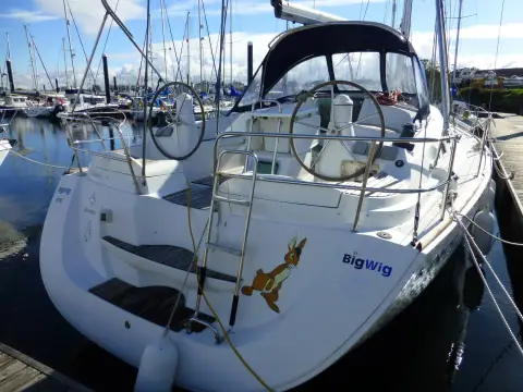 Jeanneau Sun Odyssey 42DS: stern view showing twin wheels, open transom and sprayhood in a marina