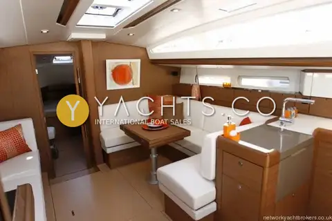 Jeanneau Sun Odyssey 44 DS: saloon with white upholstery, wood table, galley sink and view through to a cabin