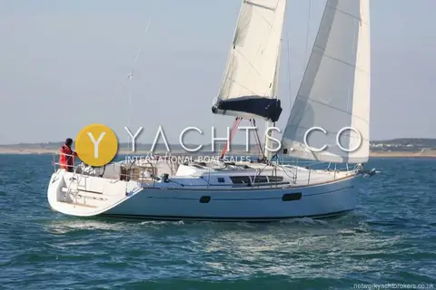 Jeanneau Sun Odyssey 44I: side view under sail near a low coastline, helmsman at the wheel